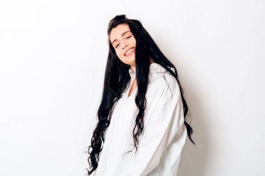 Gülümseyen genç bir kadın pozitif bir tavırla kameraya bakıyor.