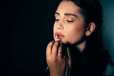 Makyaj sanatçısının eli manken dudaklarında ruj izi bırakırken manken yüzüne yakın dur. 