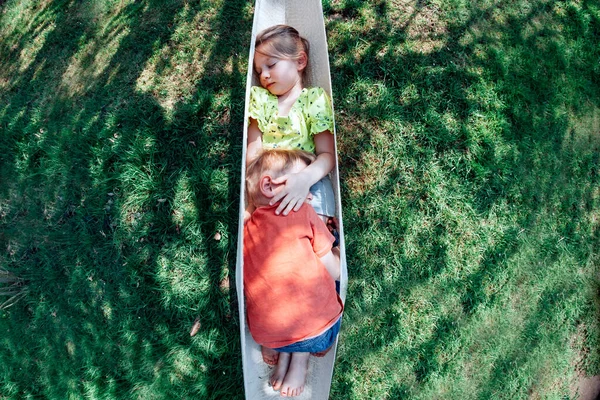 fisheye top view of siblings hugging and cuddling in the hammock outdoors in yard