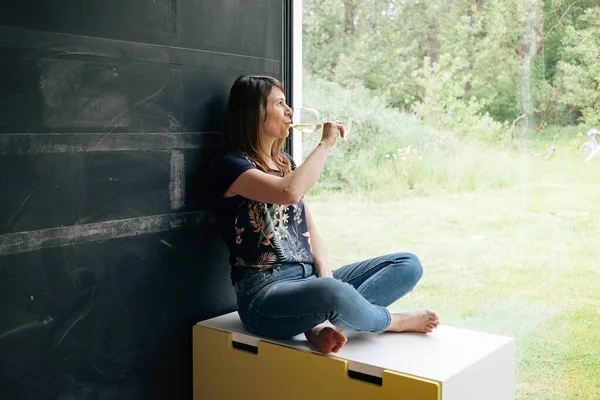 Güneşli bir günde bir kadeh şarap içen bir kadın yalnız başına - bahar karantina kederi evde.