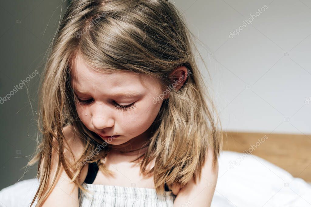 close up portrait of a little girl at home crying sadly - lockdown sadness concept