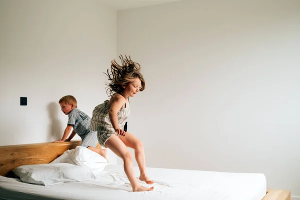 Kardeşler sabah vakti yatakta oynuyorlar. Yatakta zıplıyorlar.