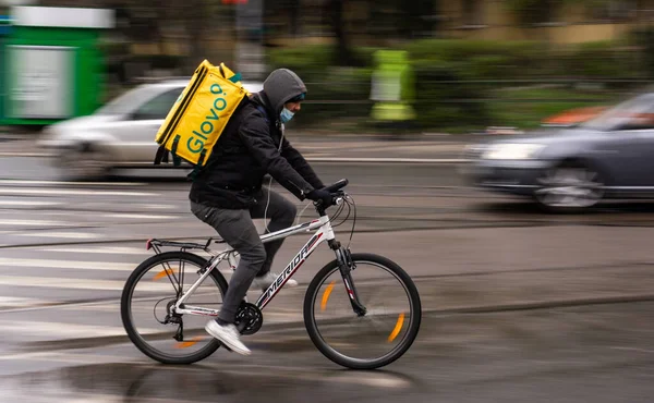 Bükreş, Romanya - 23 Mart 2020: Bisikletli bir Glovo gıda kuryesi. Restoranlar kapalıdır ve sadece acil durumlarda Coronavirus nedeniyle teslimatlara izin verilir..