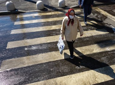 Bükreş, Romanya - 03 Nisan 2020: Maske takan yaşlı bir kadın alışverişe gitti. Romanya koronavirüs nedeniyle tecrit altında ve yaşlıların sabah 11 ile akşam 13 arasında alışveriş yapmasına izin veriliyor