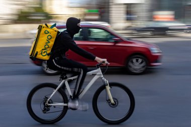 Bükreş, Romanya - 17 Mart 2020: Bisikletli bir Glovo gıda kuryesi. Restoranlar kapalıdır ve sadece acil durumlarda Coronavirus nedeniyle teslimatlara izin verilir..