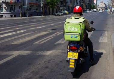 Bükreş, Romanya - 13 Nisan 2020: Bir Uber Gıda Kuryesi Romanya 'nın Bükreş kentinde yiyecek dağıtıyor.