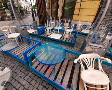 Bükreş, Romanya - 05 Mayıs 2020: Bükreş 'in Eski Kenti' ndeki koronavirüs nedeniyle olağanüstü hal sırasında geçici olarak kapatılan bir restoranın önünde masa ve sandalyeler depolandı.