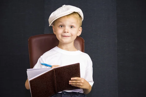 Divertente ragazzo scrive in un taccuino — Foto Stock