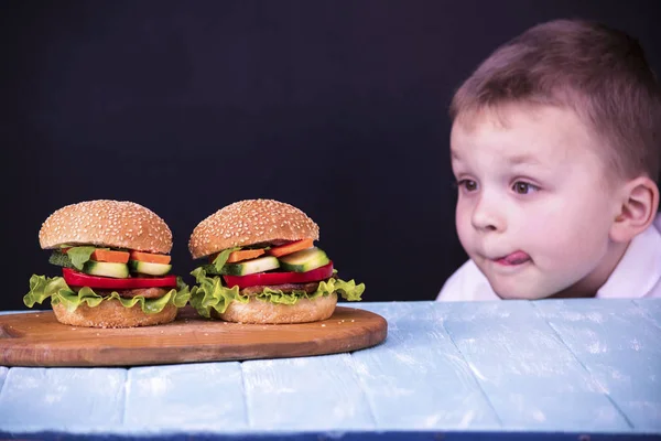 Menino olhando para um hambúrguer — Fotografia de Stock