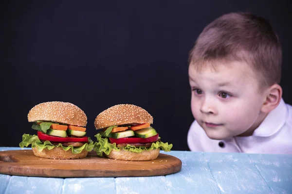 Menino olhando para um hambúrguer — Fotografia de Stock