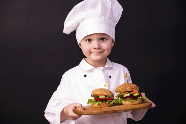 Chłopiec gotować, trzymając hamburger — Zdjęcie stockowe
