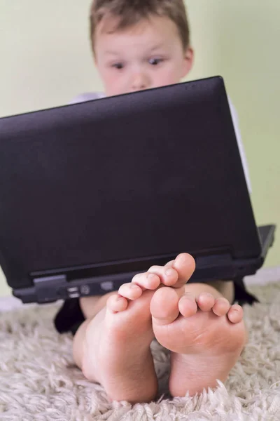 Детские ноги и ноутбук — стоковое фото