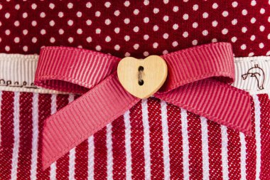 kumaş arka plan kırmızı yay ve ahşap kalp ile