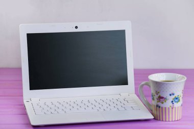 Beyaz dizüstü ve kahve fincanı pembe ahşap arka plan üzerinde