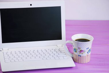 Beyaz dizüstü ve kahve fincanı pembe ahşap arka plan üzerinde