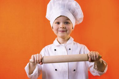 komik çocuk Şef bir oklavayla hamuru için turuncu bir arka plan üzerinde tutar.