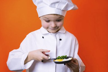 komik çocuk Şef parlak turuncu arka plan üzerinde bir tavada kızarmış yumurta tutar