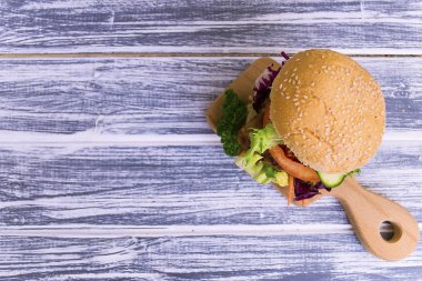 meyilli bir ahşap tahta üzerinde sebze ile kızarmış biftek sandviç