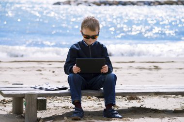 Baharda seashore tablete oynayan çocuk