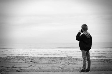 oğlan baharda deniz kıyısı, telefonda konuşuyor