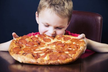 komik çocuk masada büyük bir pizza yeme