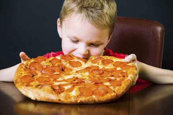 Zabawny Chłopak Jedzenie Big Pizza Przy Stole — Zdjęcie stockowe