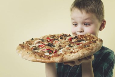 parlak sarı bir arka plan üzerinde büyük bir pizza yeme komik çocuk