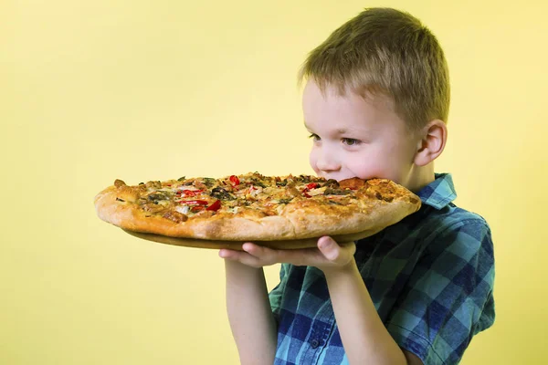 Grappige Jongen Eten Een Grote Pizza Een Helder Gele Achtergrond — Stockfoto