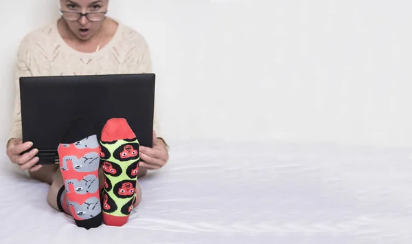 woman in glasses and in funny different socks with a drawing of animals works at a laptop