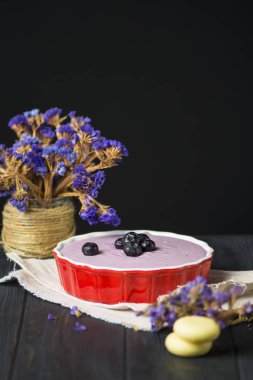 Süzme peynirli ve yaban mersinli ev yapımı cheesecake, ahşap arka planda kurabiyeler.