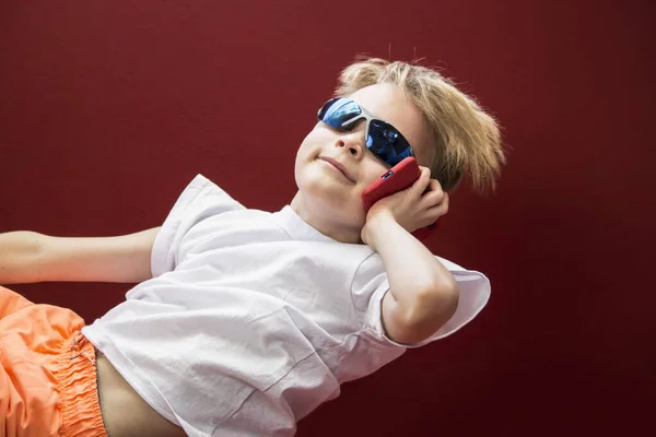 Забавный Мальчик Говорит Смартфоне Красном Фоне — стоковое фото