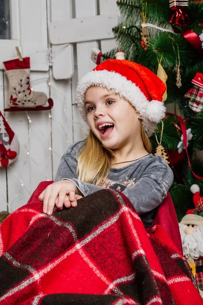 Πολύ όμορφο κορίτσι κοντά ένα χριστουγεννιάτικο δέντρο χαμογελώντας και κρατώντας ένα δώρο — Φωτογραφία Αρχείου