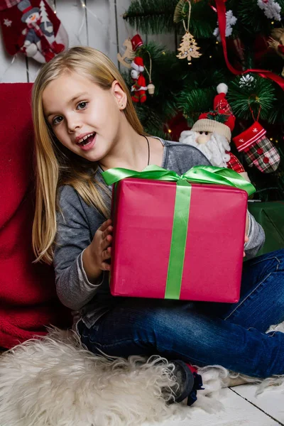 Chica muy hermosa cerca de un árbol de Navidad sonriendo y sosteniendo un — Foto de Stock