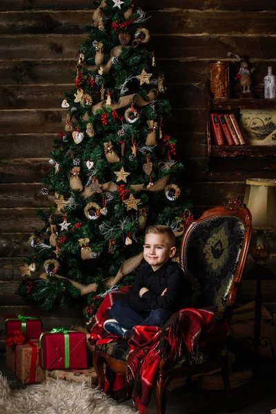 Very beautiful girl near a Christmas tree smiling and holding a present — Stock Photo, Image