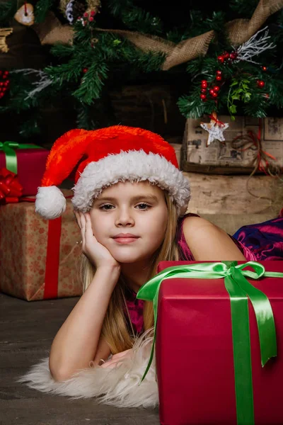 Chica muy hermosa cerca de un árbol de Navidad sonriendo y sosteniendo un regalo — Foto de Stock