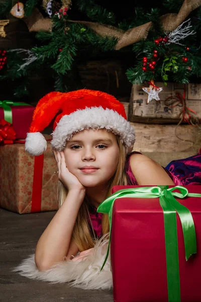 Menina muito bonita perto de uma árvore de Natal sorrindo e segurando um presente — Fotografia de Stock