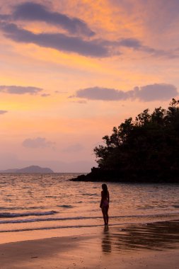 Sahilde gün batımında dans eden kaygısız bir kadın. Tatil canlılığı sağlıklı yaşam konsepti