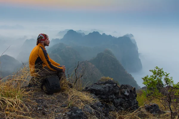 Mann sitzt auf steinerner Spitze eines hohen Berges — Stockfoto