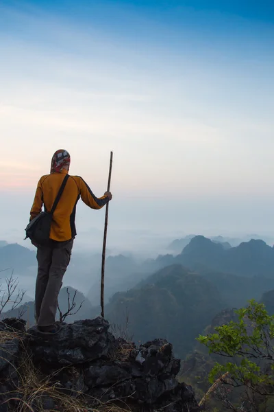 Hombre sentado en la cima de piedra de alta montaña —  Fotos de Stock