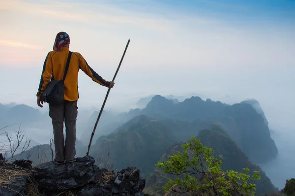 Homem sentado no topo de pedra de alta montanha — Fotografia de Stock