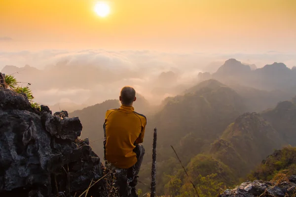 Hombre sentado en la cima de piedra de alta montaña — Foto de Stock