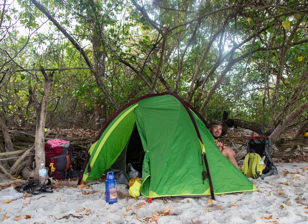 Homme assis près de la tente orange sur la plage — Photo