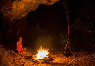 Turist kız nehir kıyısında gece kamp ateşi etrafında silüeti.