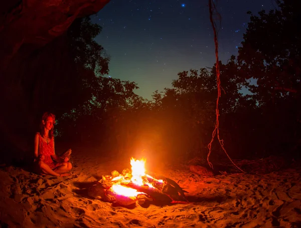 Turist kız nehir kıyısında gece kamp ateşi etrafında silüeti. — Stok fotoğraf