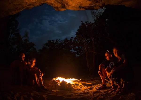 Silueta unei turiste în jurul focului de tabără noaptea pe malul râului . — Fotografie, imagine de stoc