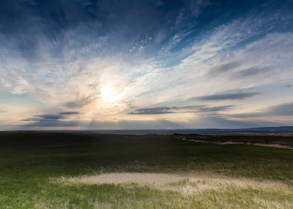 Zelené trávy a popraskané pouštní půdy nad dramatické mraky — Stock fotografie