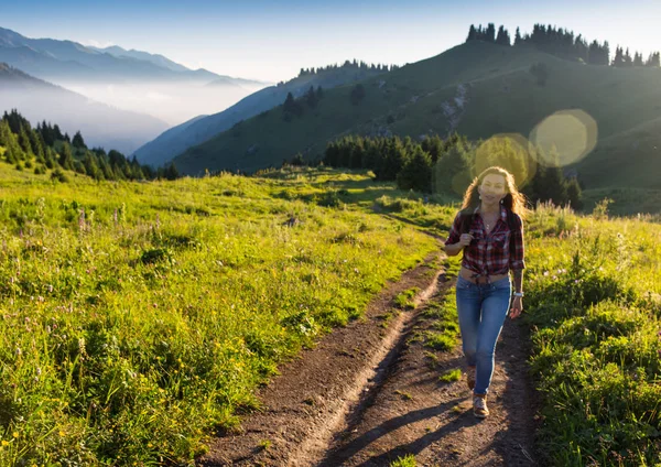 Vrouw reiziger met rugzak bedrijf hoed en kijken verbazingwekkend bergen en bos, wanderlust reizen concept, ruimte voor tekst, atmosperic episch moment — Stockfoto