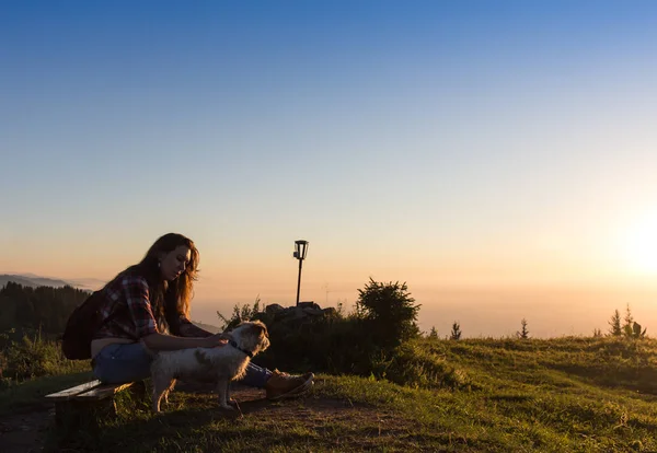 年轻女子坐在一个岩石与背包上和在眺望远方 — 图库照片