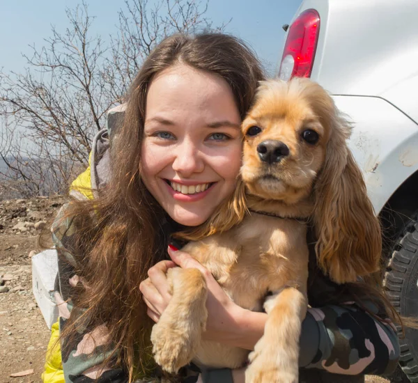 Oturma ve onun köpeği kumsalda sarılma şapka neşeli genç ve güzel kadın — Stok fotoğraf