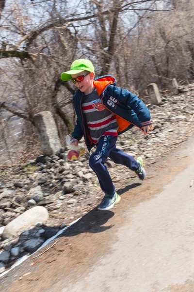 Alma-Ata, Kazachstan--09 April 2017: Amateur competities - berg halve marathon, in de uitlopers van Almaty, op de Yunat-meren. Gelukkig jongetje naar huis van school gaan — Stockfoto